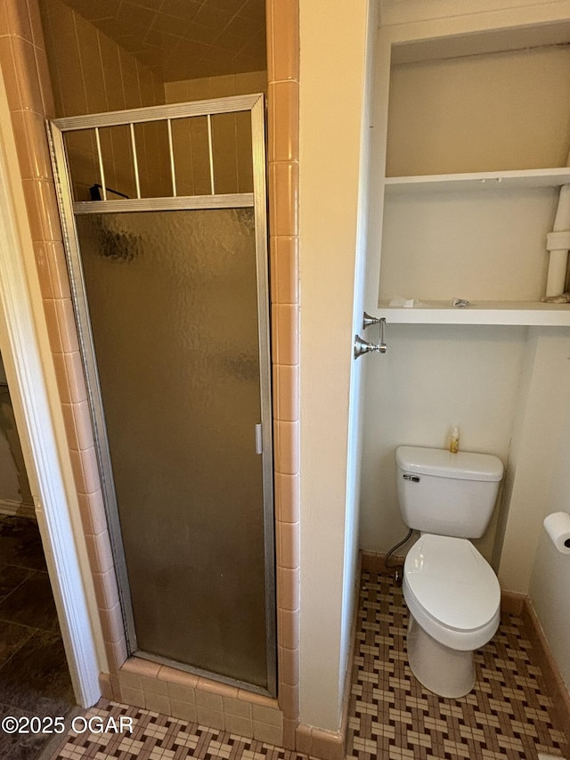 bathroom featuring toilet and a shower with shower door