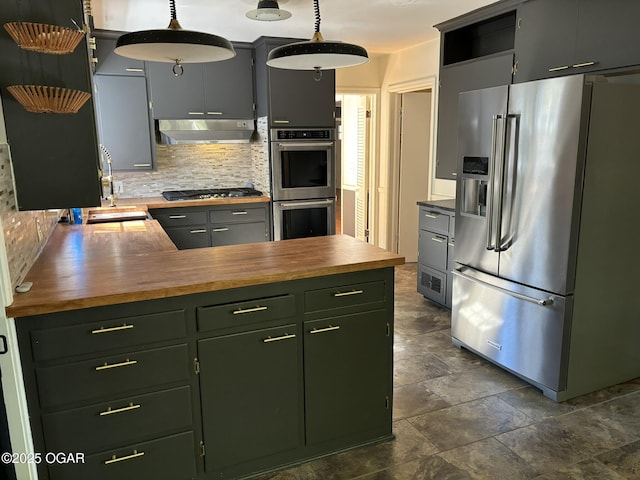 kitchen with butcher block countertops, sink, hanging light fixtures, and appliances with stainless steel finishes