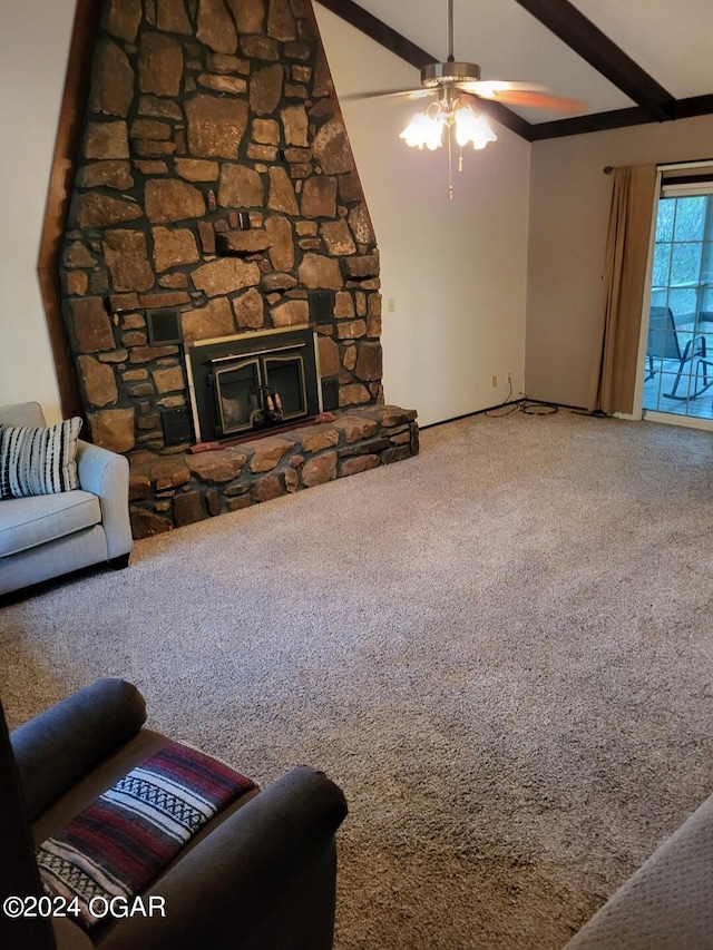 living room featuring ceiling fan, a stone fireplace, beam ceiling, and carpet