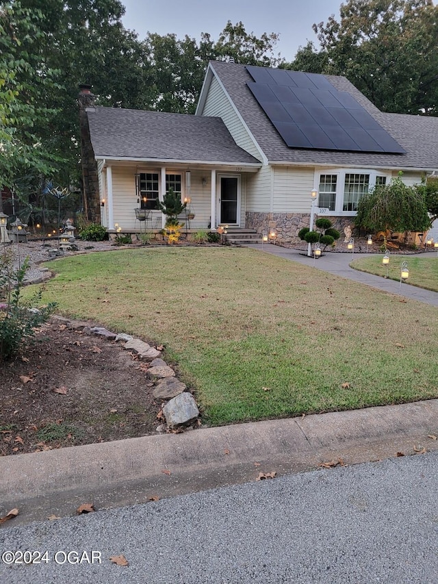 view of front of home with a porch, solar panels, and a front yard