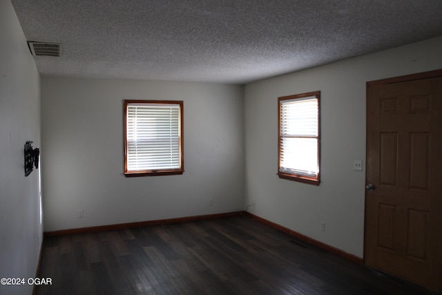 spare room featuring a textured ceiling and dark hardwood / wood-style floors