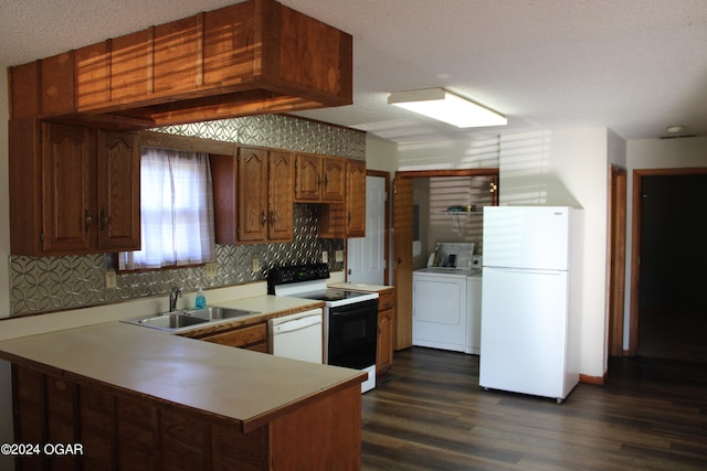 kitchen featuring dark hardwood / wood-style floors, sink, washing machine and clothes dryer, kitchen peninsula, and white appliances