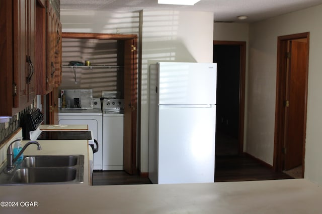 kitchen featuring dark wood-type flooring, white refrigerator, separate washer and dryer, a textured ceiling, and sink