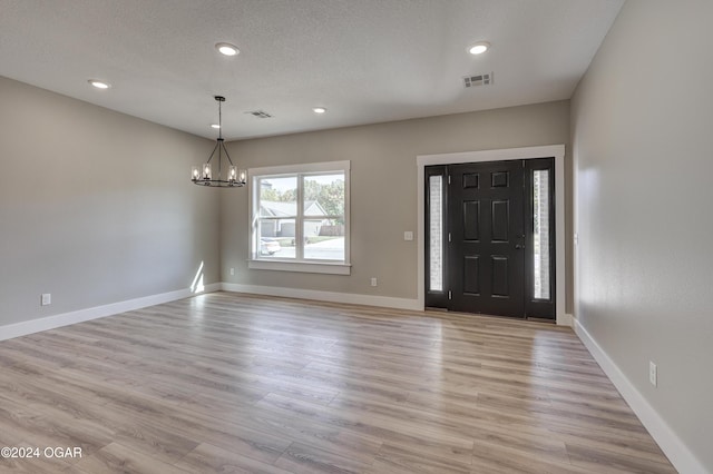 foyer with a chandelier, a textured ceiling, and light hardwood / wood-style floors