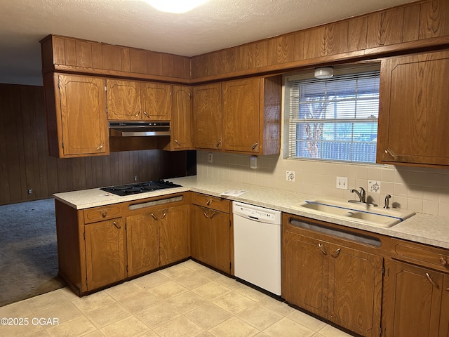 kitchen with white dishwasher, sink, black gas cooktop, and wood walls