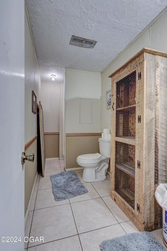 bathroom with a textured ceiling, tile patterned flooring, and toilet