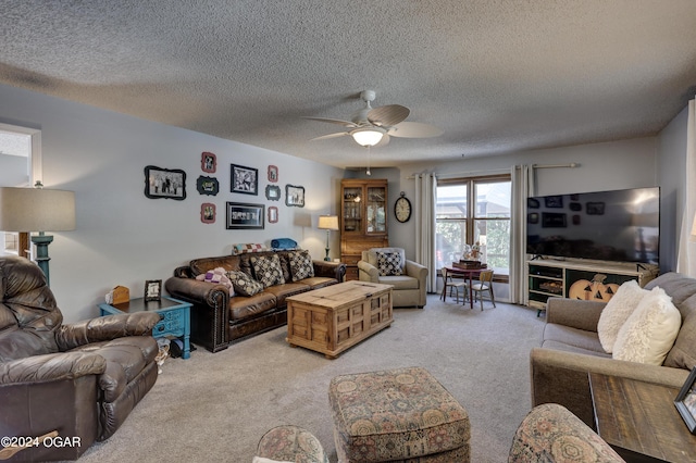 living room featuring light carpet, ceiling fan, and a textured ceiling