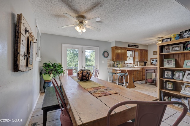 tiled dining room with a textured ceiling, ceiling fan, and sink