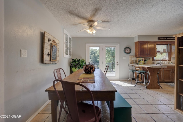 tiled dining area with ceiling fan and a textured ceiling