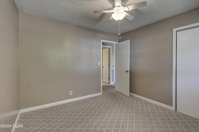 unfurnished bedroom featuring a textured ceiling, light colored carpet, and ceiling fan