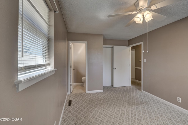 unfurnished bedroom with ensuite bath, light carpet, a textured ceiling, and ceiling fan