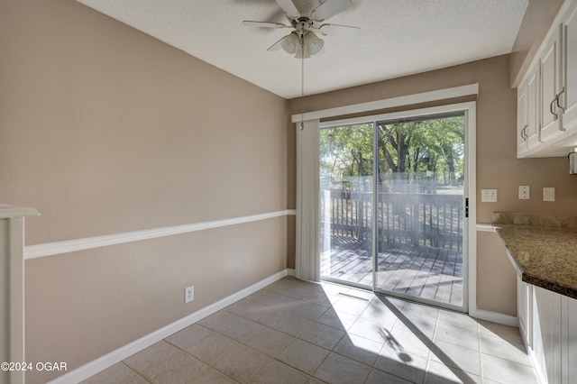 unfurnished dining area with ceiling fan, a textured ceiling, and light tile patterned floors