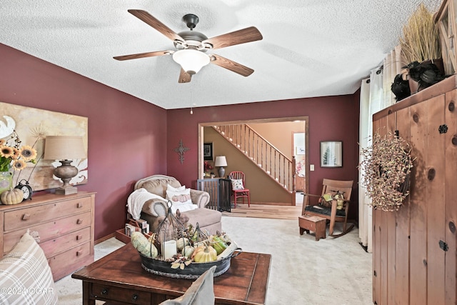 living room with light carpet, ceiling fan, and a textured ceiling