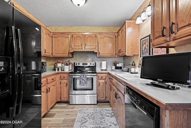 kitchen with a textured ceiling, light hardwood / wood-style flooring, and black appliances