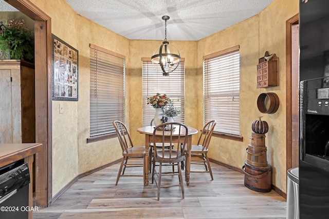 dining space with an inviting chandelier, light hardwood / wood-style floors, and a textured ceiling