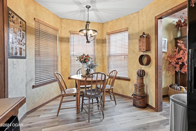 dining room with a notable chandelier, wood-type flooring, and a textured ceiling