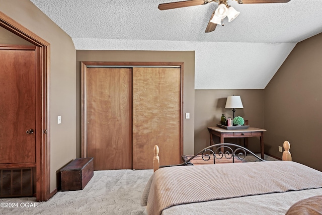 bedroom featuring carpet flooring, ceiling fan, a closet, vaulted ceiling, and a textured ceiling