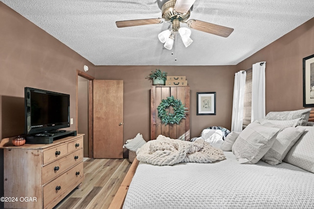 bedroom featuring ceiling fan, a textured ceiling, and light hardwood / wood-style flooring