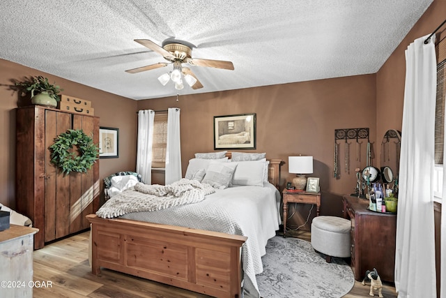 bedroom featuring light wood-type flooring, ceiling fan, and a textured ceiling