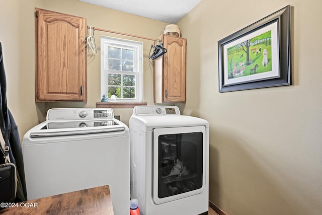 laundry area with washing machine and dryer, cabinets, and a textured ceiling