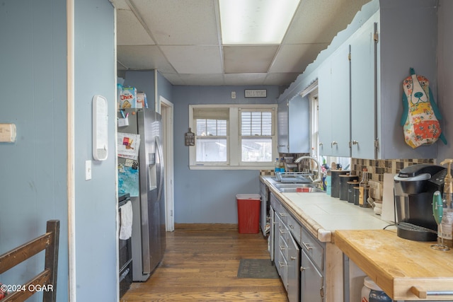 kitchen with sink, dark wood-type flooring, backsplash, tile countertops, and a paneled ceiling