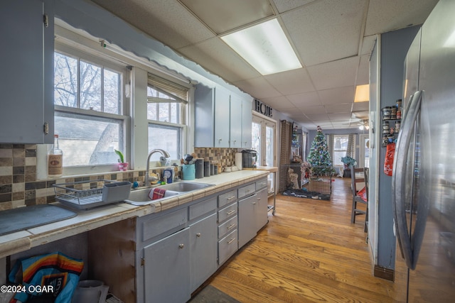 kitchen with a paneled ceiling, stainless steel refrigerator, plenty of natural light, and backsplash