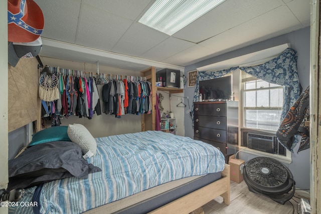 bedroom with a paneled ceiling, cooling unit, and hardwood / wood-style floors