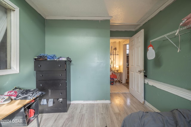 interior space with a textured ceiling, crown molding, and light hardwood / wood-style flooring