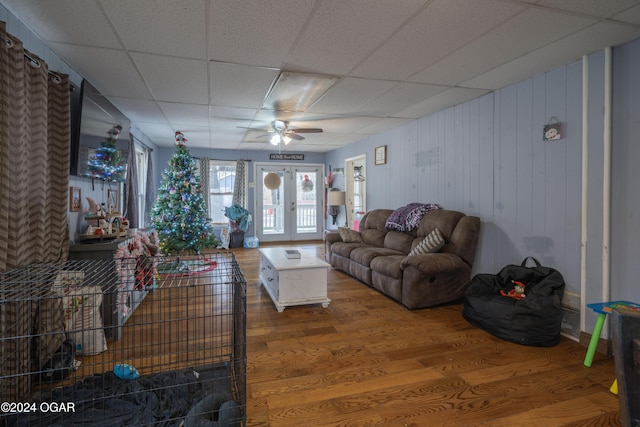 living room with ceiling fan, a drop ceiling, wood-type flooring, and french doors