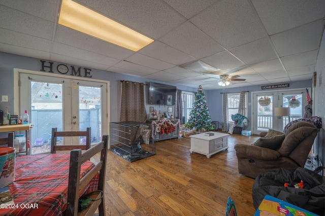 living room with a paneled ceiling, a healthy amount of sunlight, french doors, and wood-type flooring