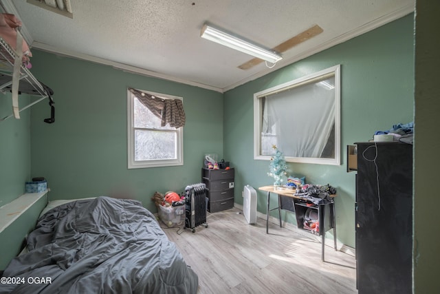 bedroom with a textured ceiling, light wood-type flooring, and crown molding