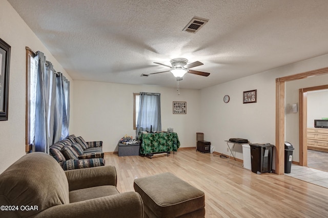 living room featuring ceiling fan, a textured ceiling, light hardwood / wood-style flooring, and a wealth of natural light