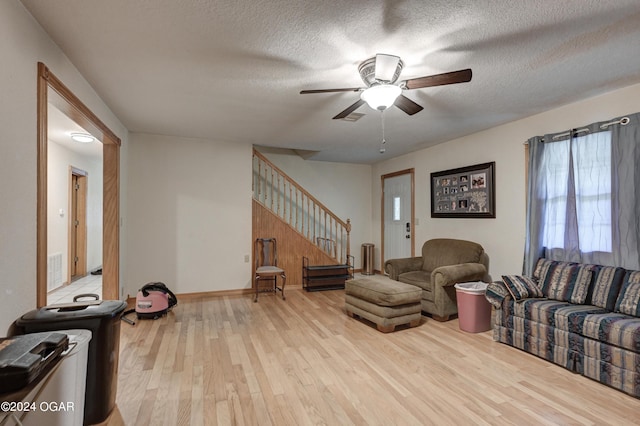 living room featuring ceiling fan, a textured ceiling, and light hardwood / wood-style floors