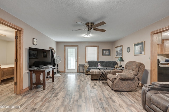 living room with ceiling fan, a textured ceiling, and light hardwood / wood-style floors