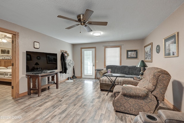 living room featuring light wood-type flooring, ceiling fan, and a textured ceiling