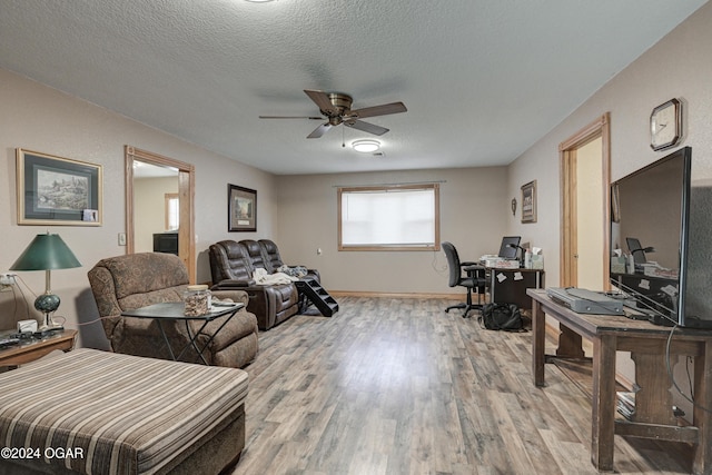 living room with light wood-type flooring, ceiling fan, and a textured ceiling