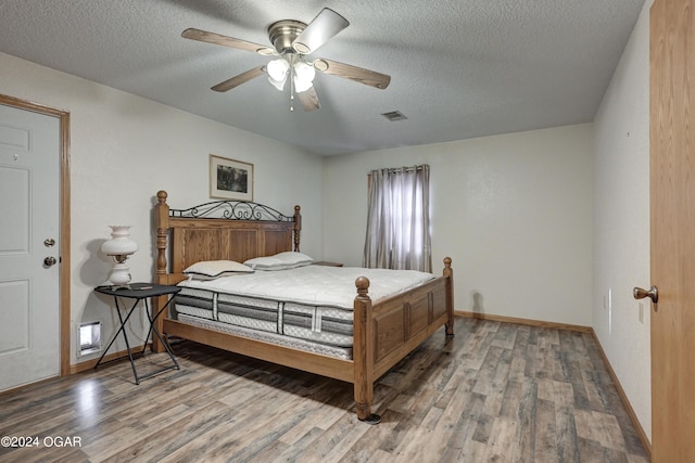 bedroom with hardwood / wood-style floors, a textured ceiling, and ceiling fan