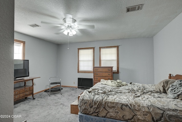 carpeted bedroom featuring multiple windows, ceiling fan, and a textured ceiling