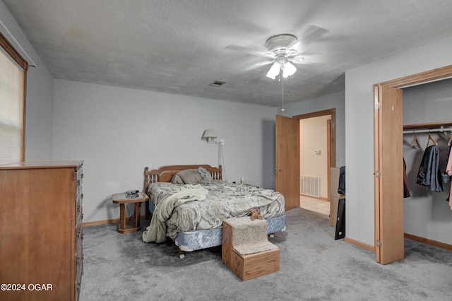 bedroom with a closet, light colored carpet, a textured ceiling, and ceiling fan