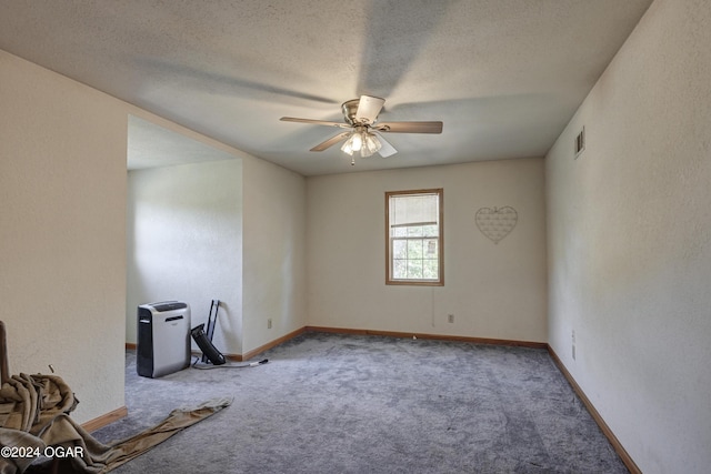 carpeted spare room featuring ceiling fan and a textured ceiling