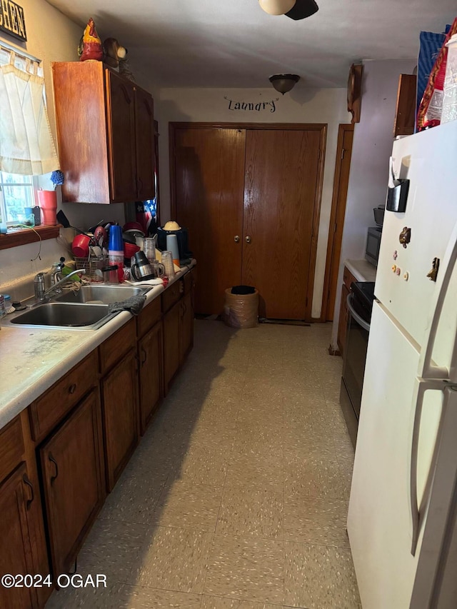 kitchen with stove, white fridge, and sink