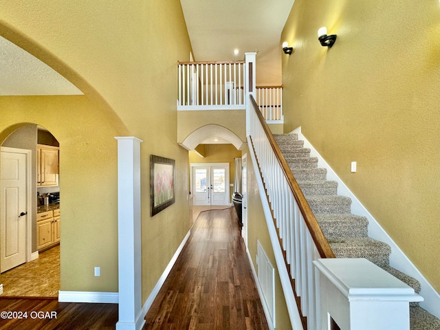 stairway with french doors and hardwood / wood-style floors