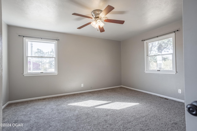 empty room with ceiling fan, a healthy amount of sunlight, and carpet floors