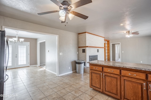 kitchen featuring light tile patterned floors, decorative light fixtures, a fireplace, and stainless steel fridge