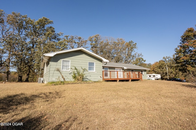 back of house with central air condition unit, a deck, and a lawn