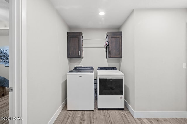 laundry room featuring cabinets, light hardwood / wood-style flooring, and washing machine and clothes dryer