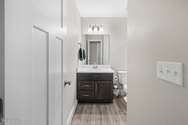 bathroom with vanity, wood-type flooring, and toilet