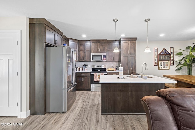 kitchen featuring appliances with stainless steel finishes, sink, dark brown cabinetry, pendant lighting, and light hardwood / wood-style flooring