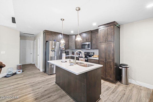 kitchen with dark brown cabinets, a kitchen island with sink, stainless steel appliances, and light wood-type flooring