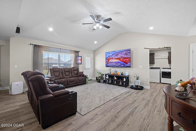 living room with ceiling fan, lofted ceiling, washer and clothes dryer, and light wood-type flooring